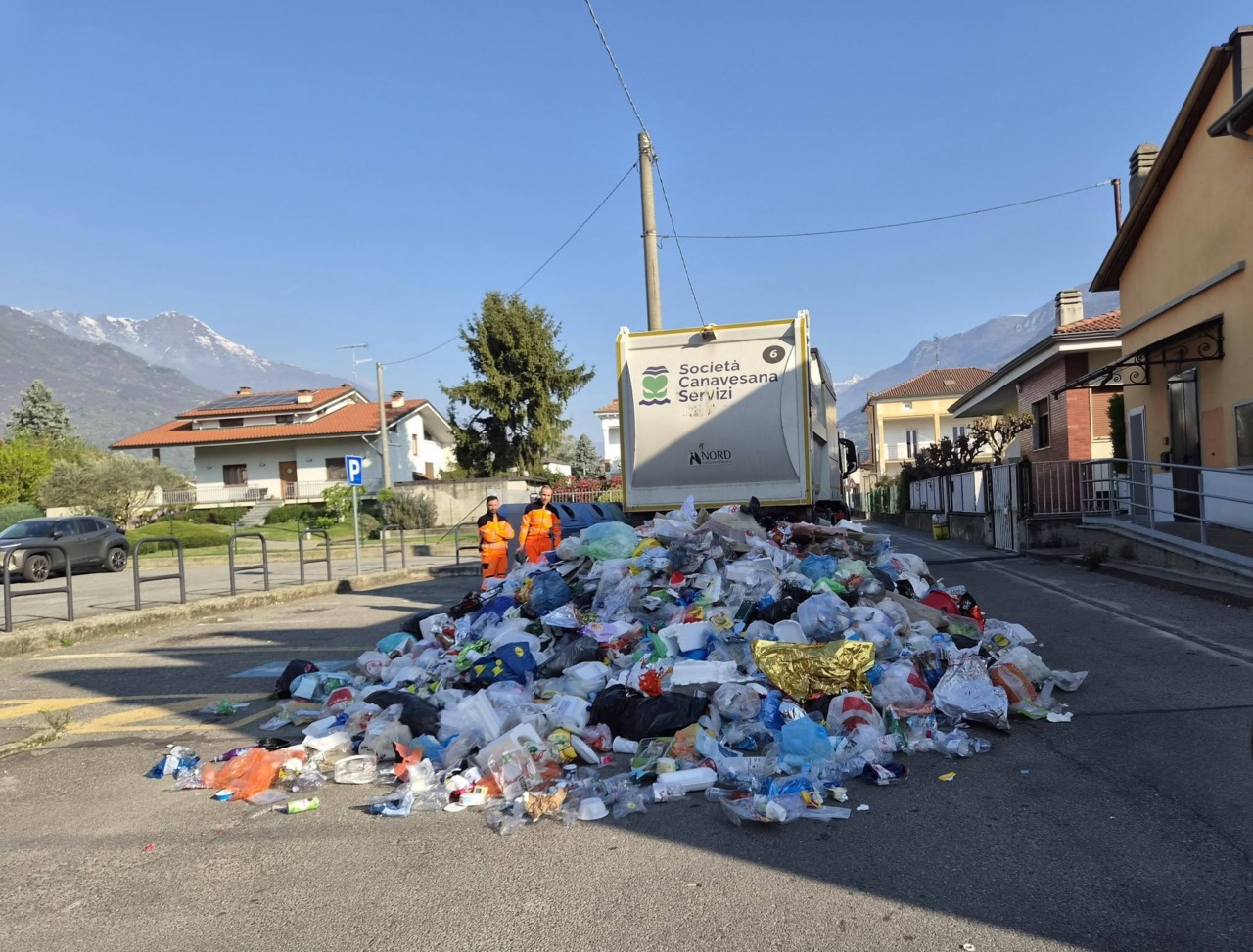 Camion della spazzatura perde il carico di rifiuti in strada