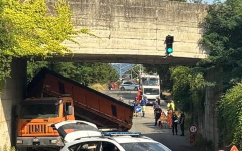 Camion con il cassone alzato si incastra sotto il cavalcavia: traffico in tilt e paura per la ferrovia